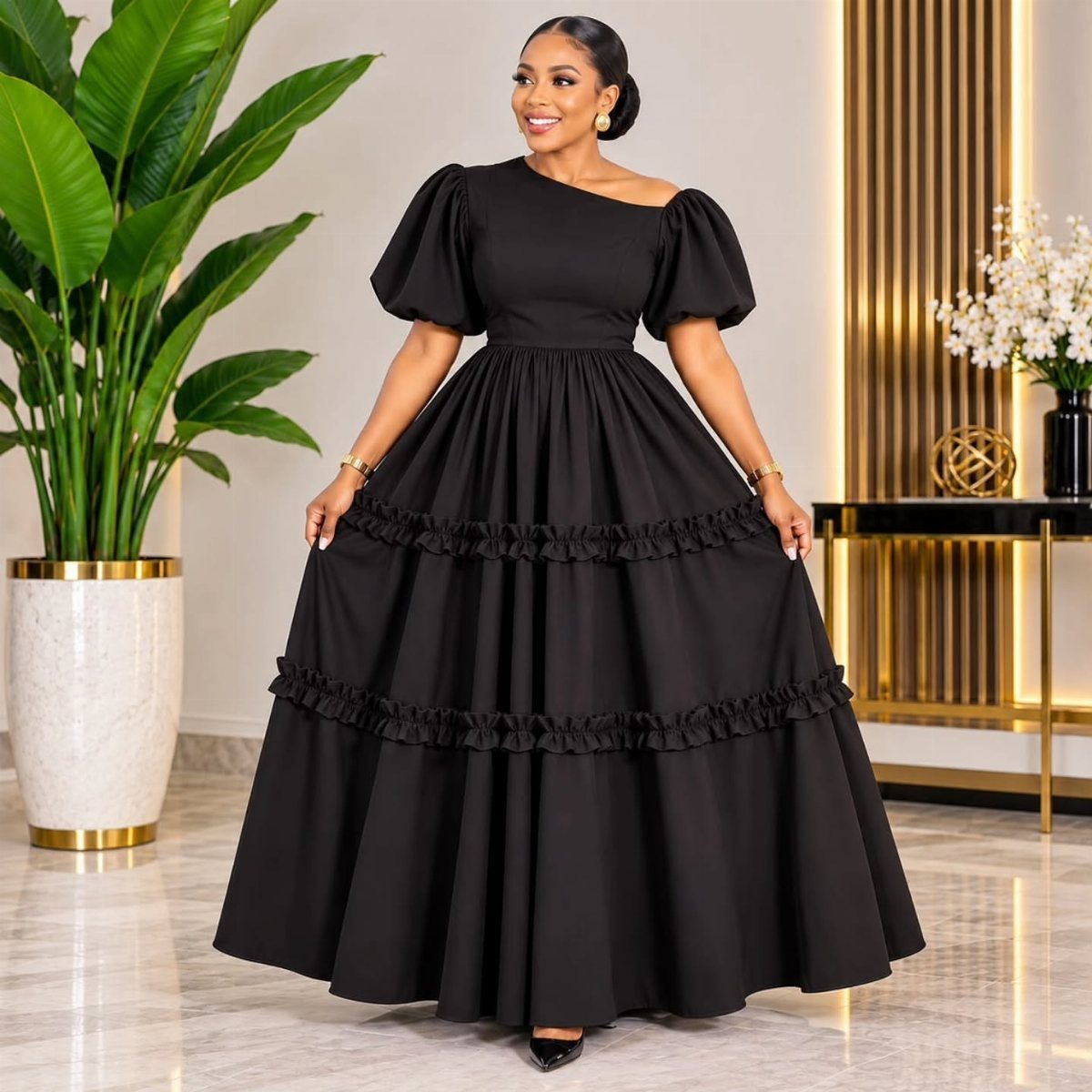 Woman in a black tiered ruffle maxi dress with puff sleeves in a modern room.