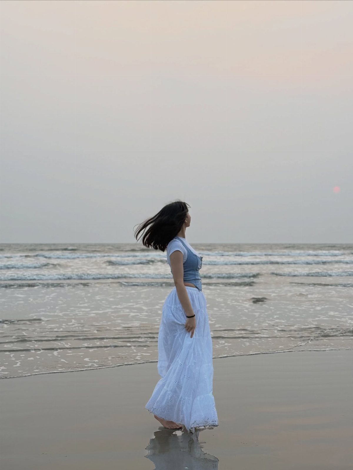 Fall Beach Outfits: 20 Ideas for Your Coastal Getaway 17 Woman in a blue top and white maxi skirt standing on a beach.
