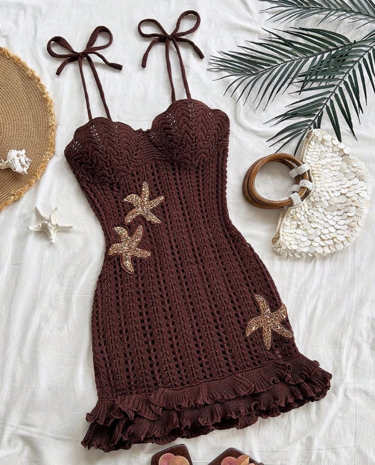 Fall Beach Outfits: 20 Ideas for Your Coastal Getaway 7 Brown crochet mini dress with starfish details and beach accessories on white fabric.