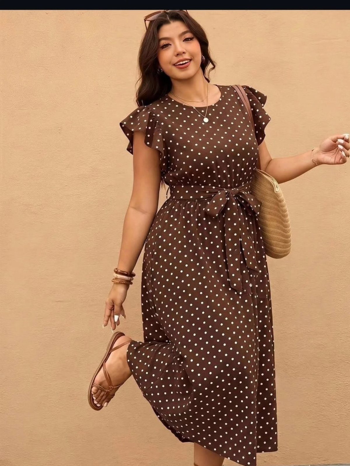 Fall Beach Outfits: 20 Ideas for Your Coastal Getaway 5 Woman in a brown polka dot midi dress with a straw bag and sandals.