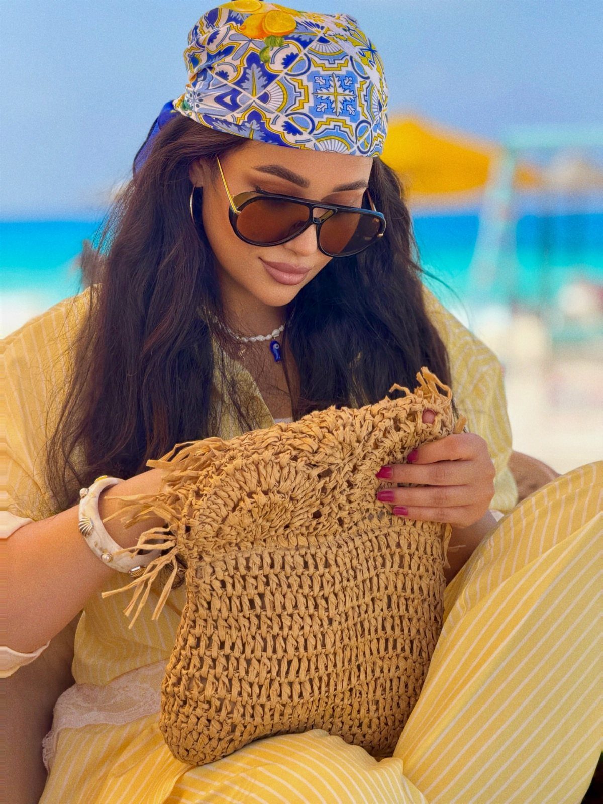 Fall Beach Outfits: 20 Ideas for Your Coastal Getaway 14 Woman wearing large dark sunglasses and a patterned headscarf on a sunny beach.