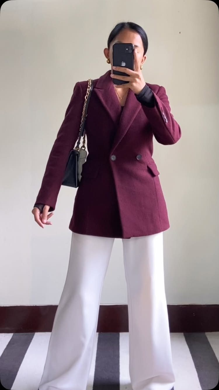 Woman wearing a burgundy double-breasted blazer and wide-leg white trousers for a tailored look.
