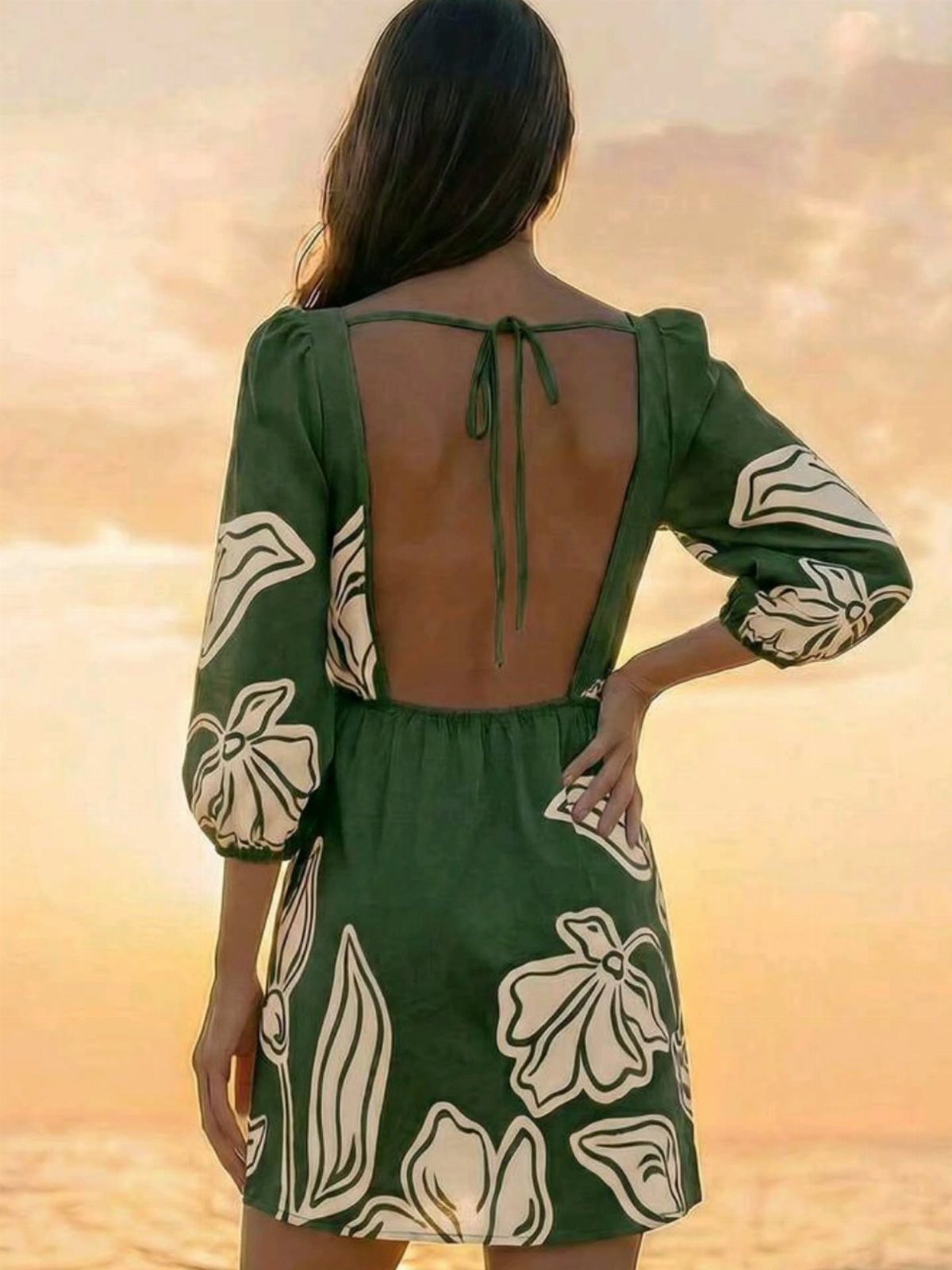Woman from behind in a short green floral dress with an open back.