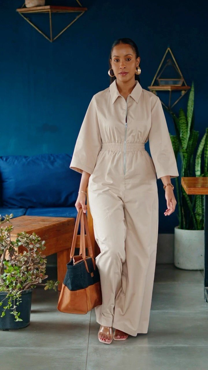 Woman wearing a beige neutral jumpsuit with wide legs and a cinched waist.
