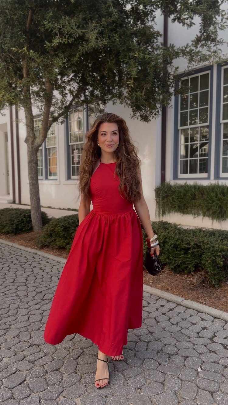 Woman wearing a sleeveless red midi dress and black heels on a cobblestone path