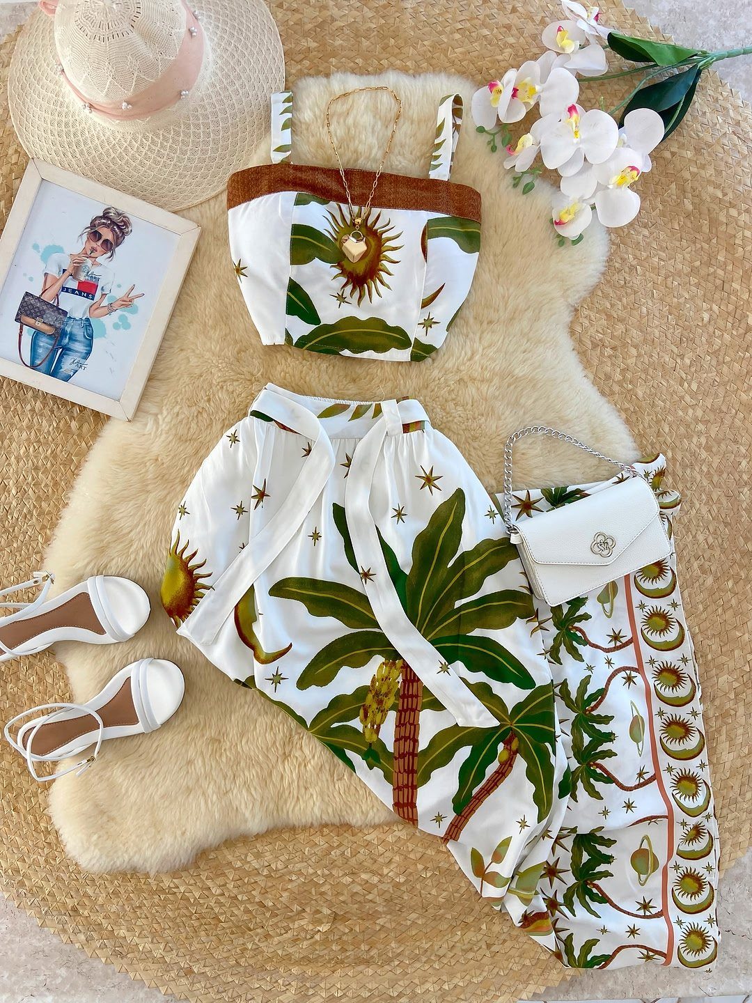 White two-piece outfit with palm tree prints, straw hat, and white sandals.