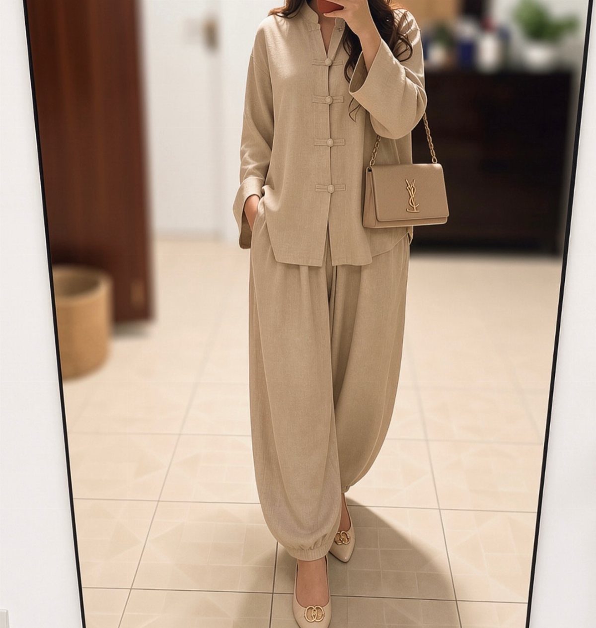 Person wearing a matching beige linen blouse and loose trousers with a shoulder bag.