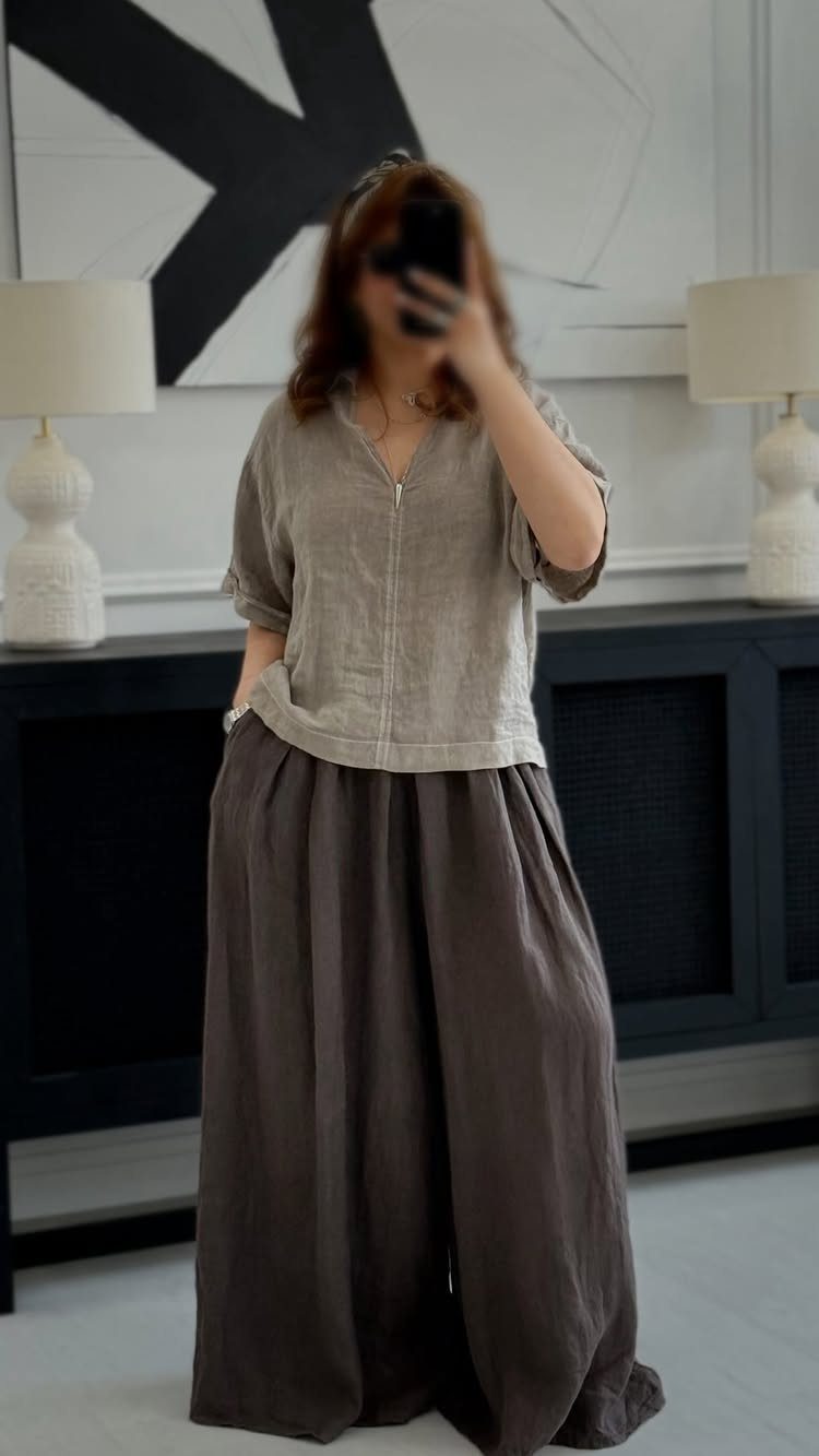 A person wearing a grey linen top and dark brown wide-leg linen pants.