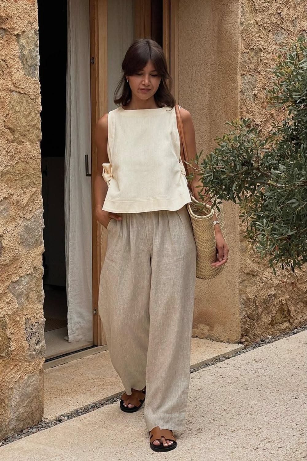 Woman wearing a cream linen top and beige wide-leg linen pants standing outdoors.