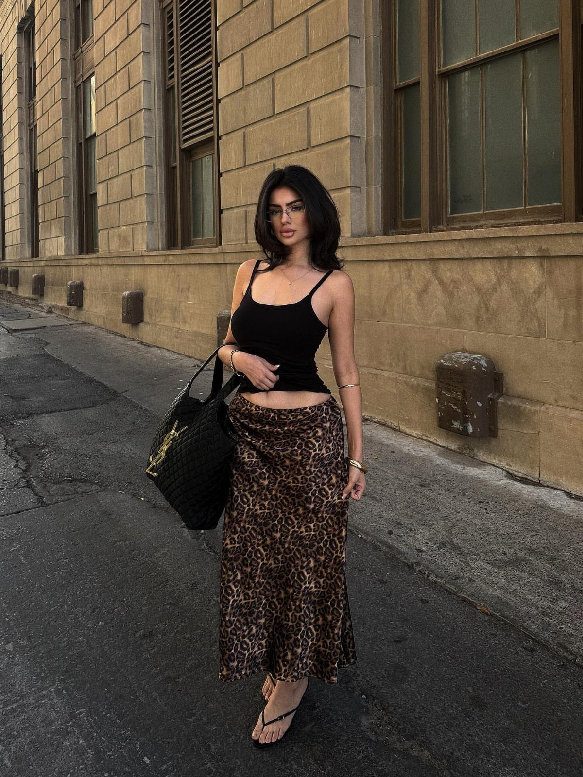 Woman in leopard print maxi skirt and black cropped tank top on city street