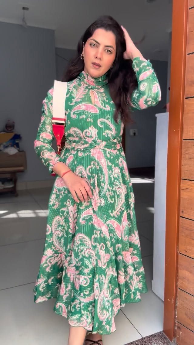 Woman wearing a green and pink paisley print long-sleeved maxi dress indoors.