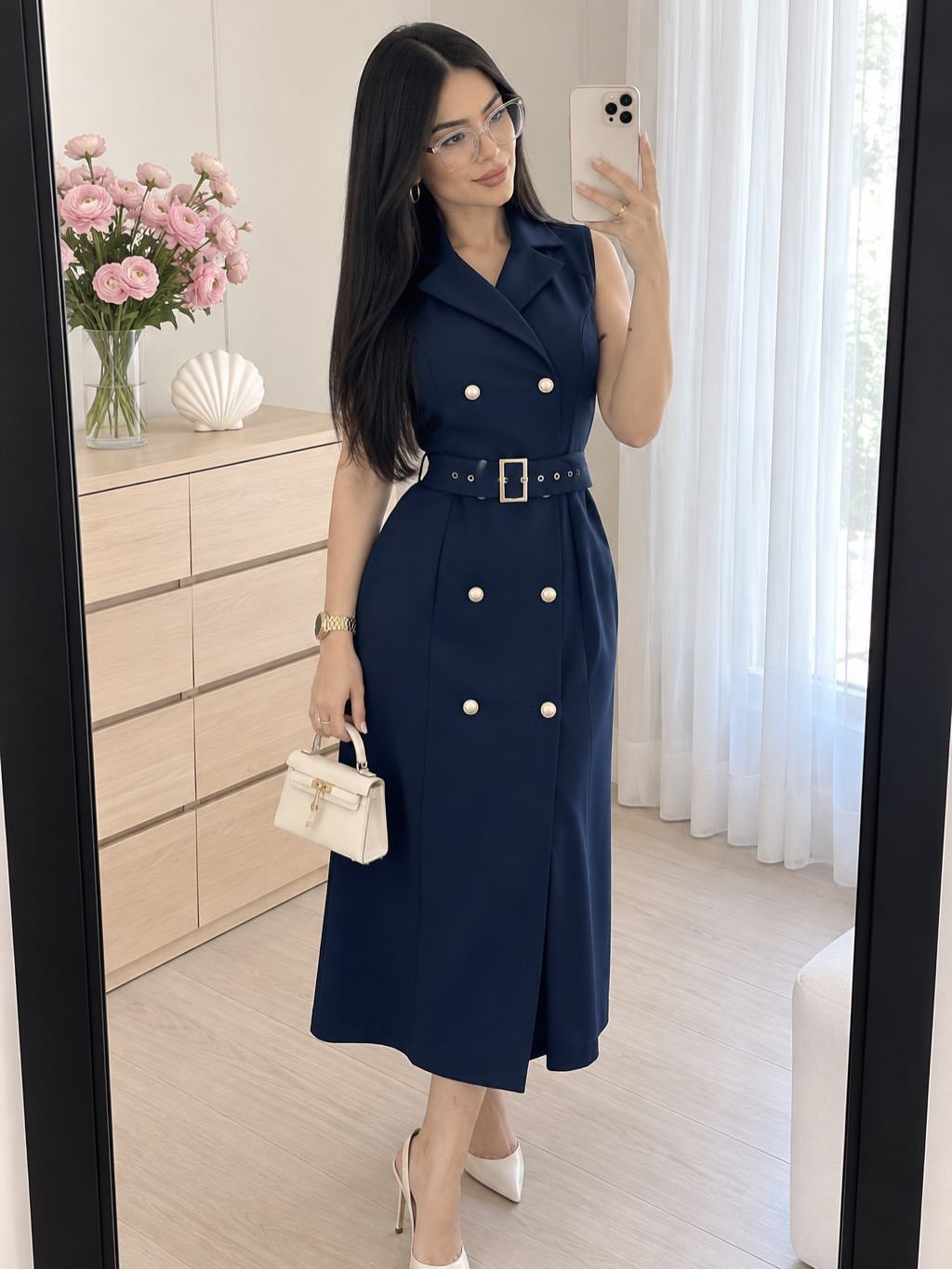 9 Navy Blue Outfit Ideas for Every Setting 5 Woman posing in a sleeveless navy blue blazer dress with gold buttons and a belt.