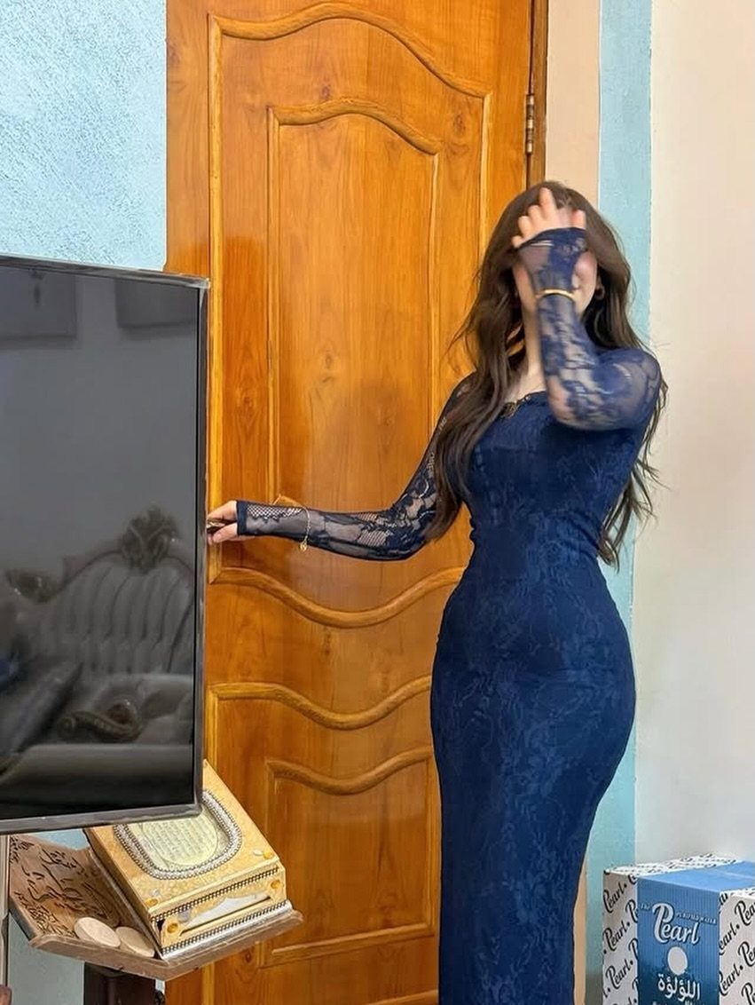 9 Navy Blue Outfit Ideas for Every Setting 9 A woman in a long-sleeved navy blue lace dress standing by a wooden door.