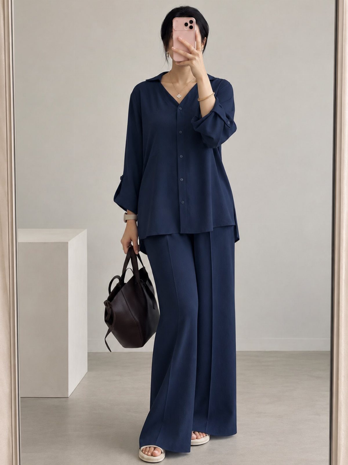 9 Navy Blue Outfit Ideas for Every Setting 4 Woman wearing a navy blue two-piece outfit with a long tunic and wide-leg trousers.