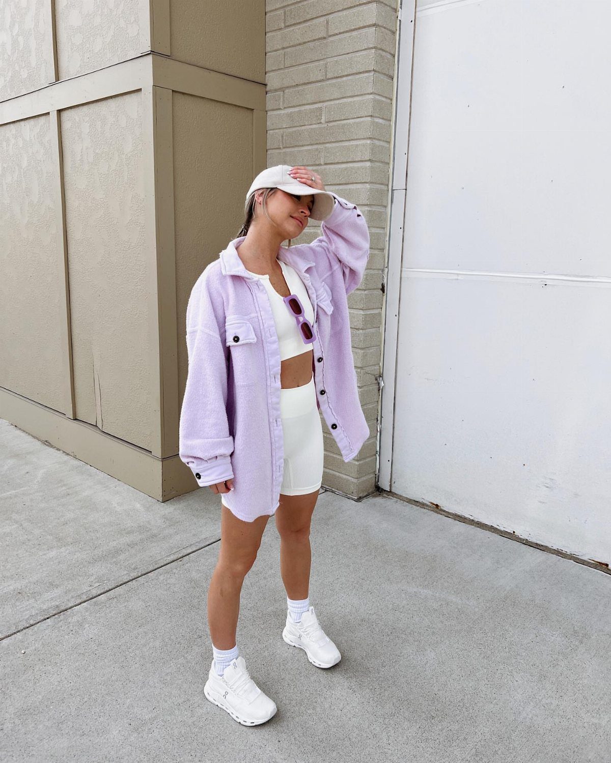 10 Outfit Ideas for Mom: From Classic Days to Mom's Nights Out 8 Woman in a purple shirt, white sports bra, white shorts, and white sneakers standing outdoors.