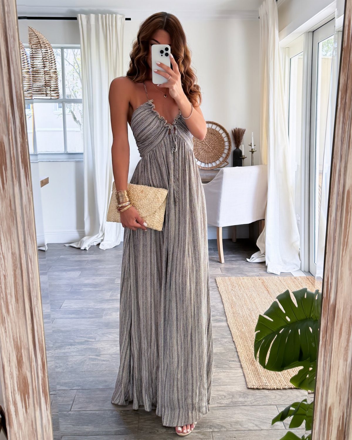 10 Outfit Ideas for Mom: From Classic Days to Mom's Nights Out 3 Woman in a long patterned strappy maxi dress holding a straw clutch in a mirror selfie.