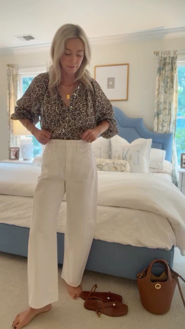 10 Outfit Ideas for Mom: From Classic Days to Mom's Nights Out 10 Blonde woman wearing a patterned blouse and white wide-leg trousers standing in a bedroom.