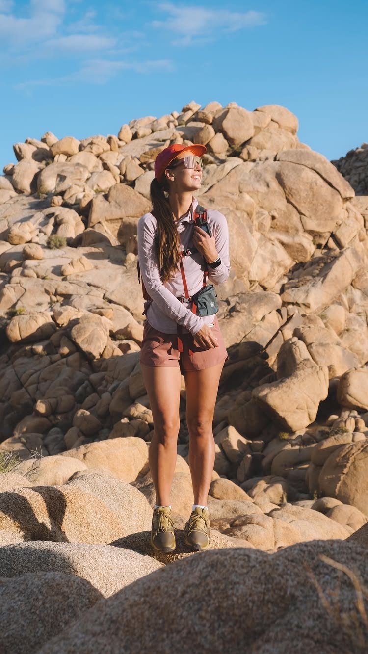 Outfit for Vacation: 13 Ideas for Every Island Moment 6 Woman in hiking gear standing amidst large desert boulders under a blue sky.