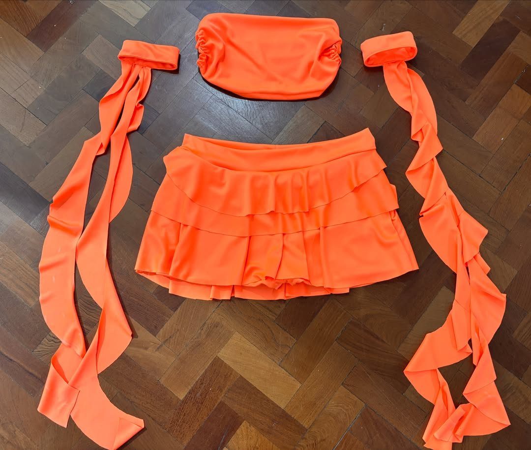 Outfit for Vacation: 13 Ideas for Every Island Moment 4 Orange ruched tube top and tiered ruffled skirt laid on a wooden floor.
