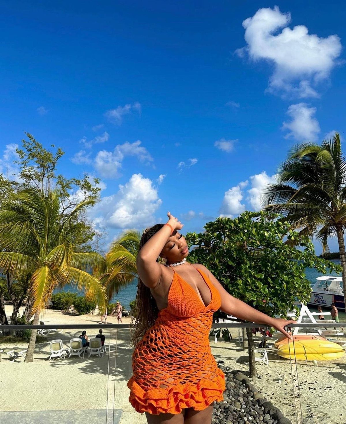 Outfit Ideas for Cancun: 13 Looks for Every Occasion 2 Woman in a bright orange crochet mini dress posing on a tropical beach.