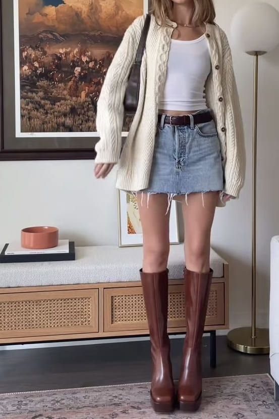 Woman wearing a cream cardigan, light-blue denim mini skirt, and brown platform boots.