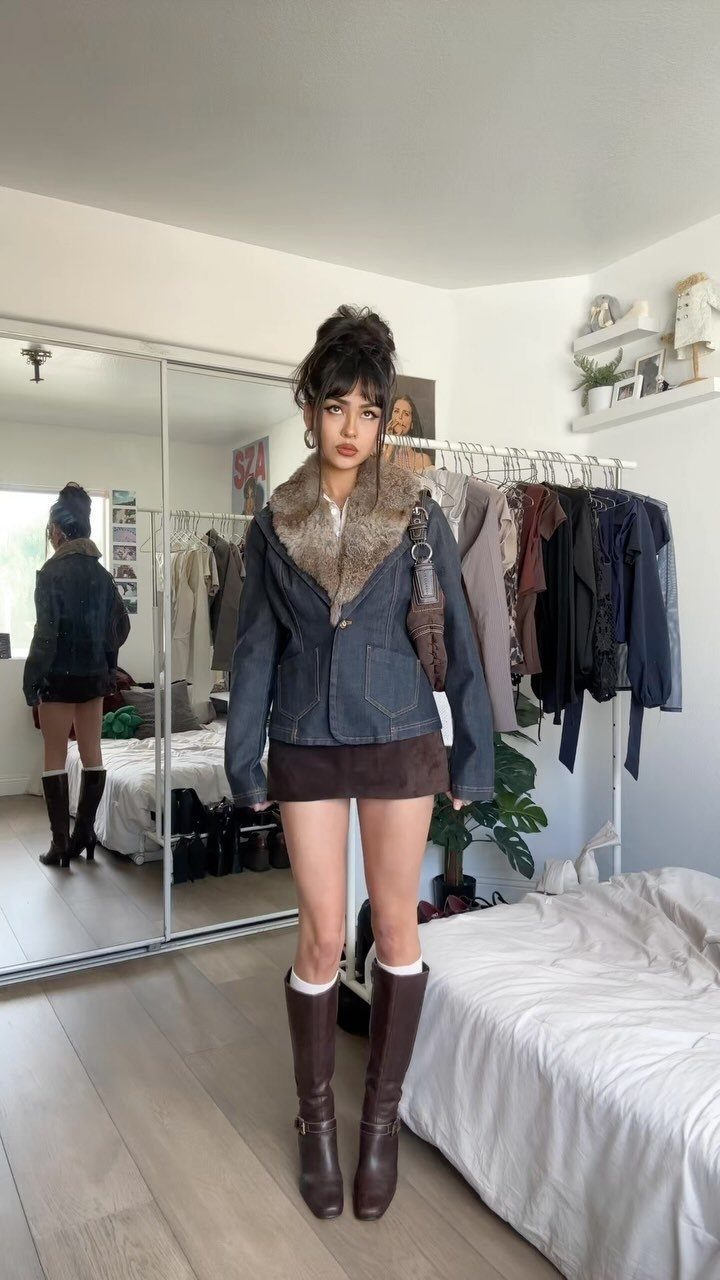 Woman wearing a denim jacket, brown mini skirt, and tall brown leather boots.