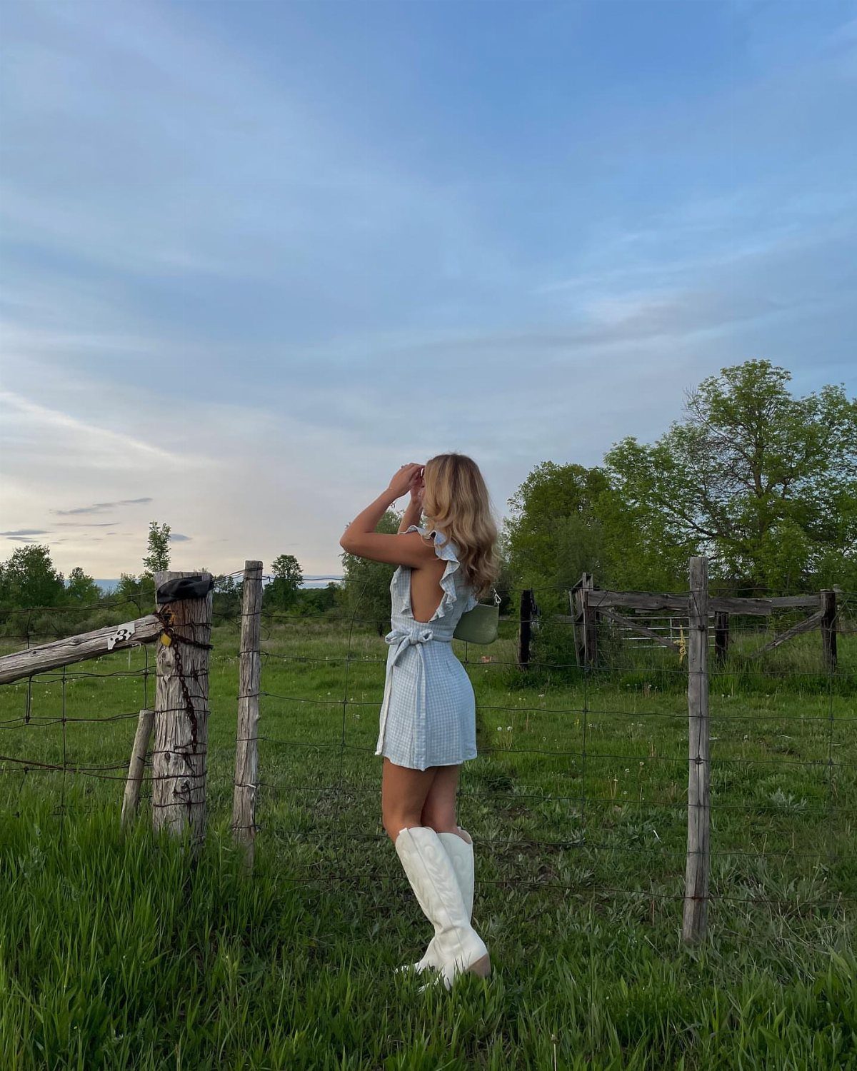 Outfit with Cowboy Boots: 6 Ways From Casual to Dressy 3 Woman in a light blue dress and white cowboy boots standing in a field.