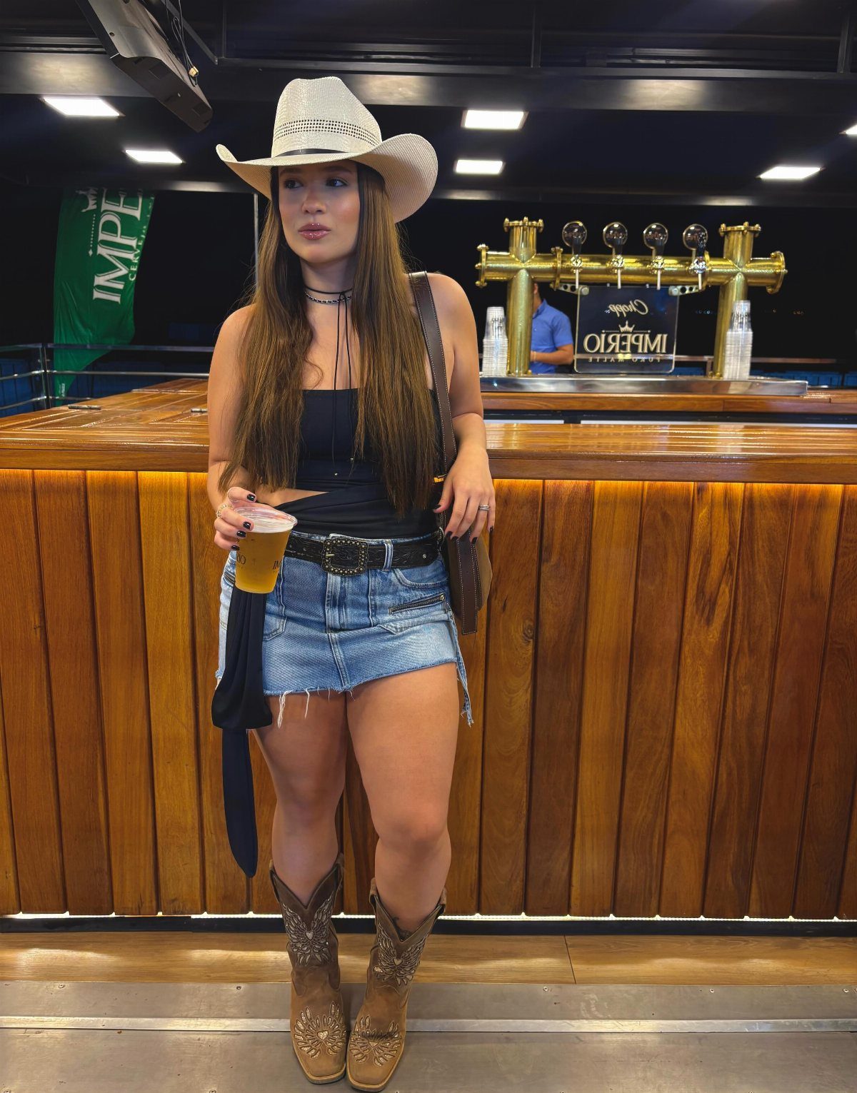 Outfit with Cowboy Boots: 6 Ways From Casual to Dressy 2 Woman in a denim mini skirt and brown cowboy boots at a bar.