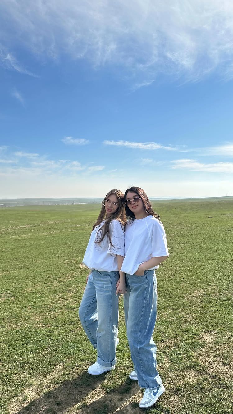 11 Outfits for Teens: Street to Semiformal Style Ideas 1 Two young women posing in a field wearing white t-shirts and baggy blue jeans.