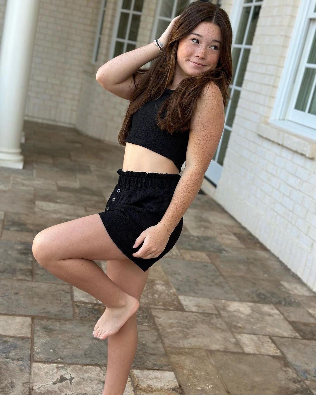 11 Outfits for Teens: Street to Semiformal Style Ideas 2 Teenage girl posing in a black ribbed crop top and matching high-waisted shorts.