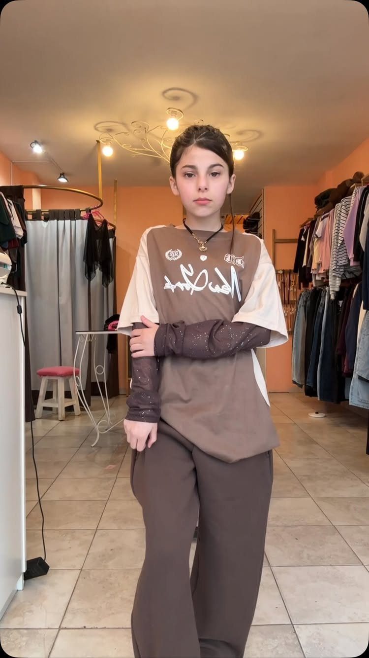 11 Outfits for Teens: Street to Semiformal Style Ideas 10 A young woman posing in a boutique wearing an oversized brown t-shirt and wide-leg pants.