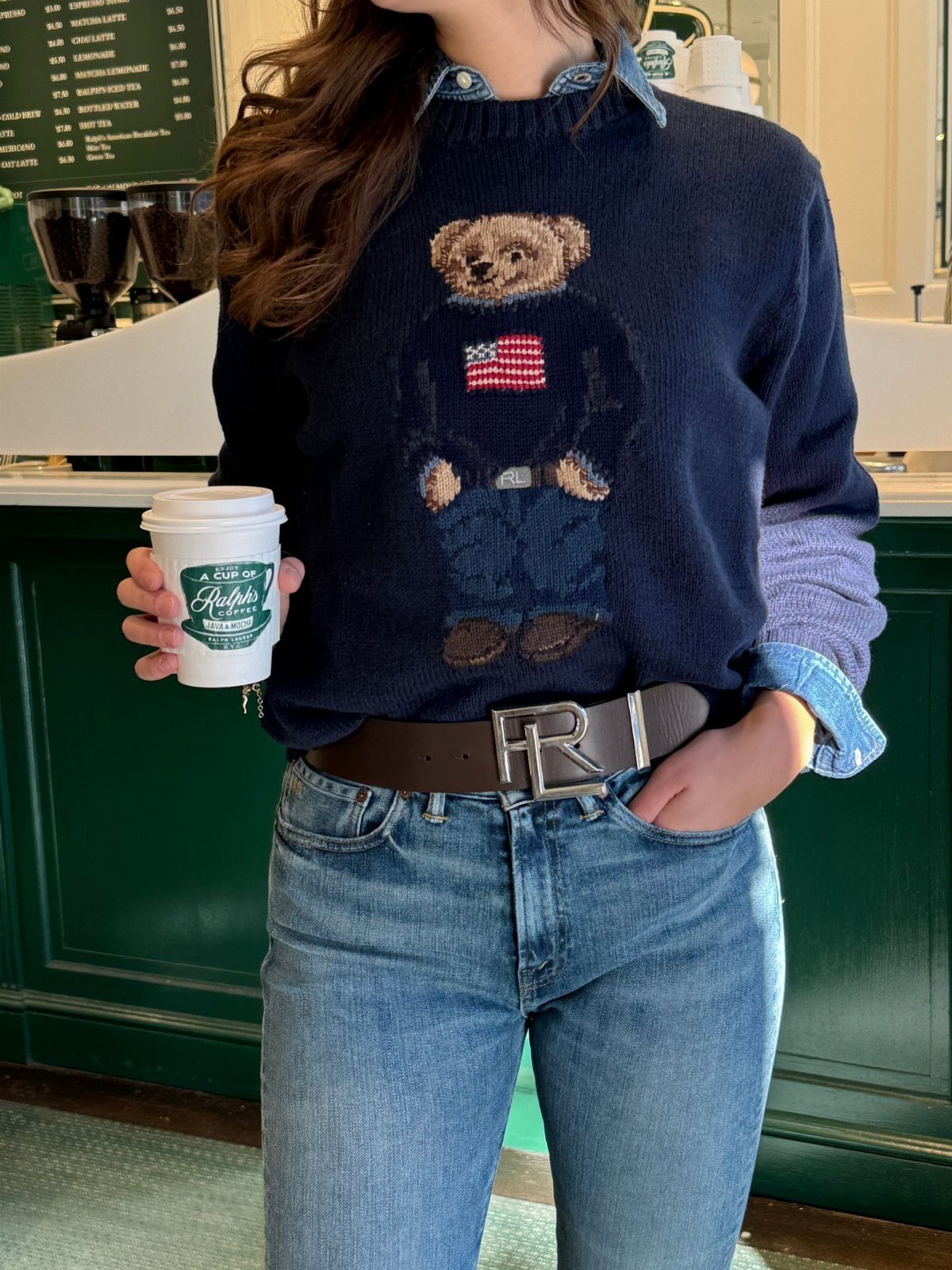 Navy bear sweater and blue jeans outfit with a collared shirt and coffee cup.