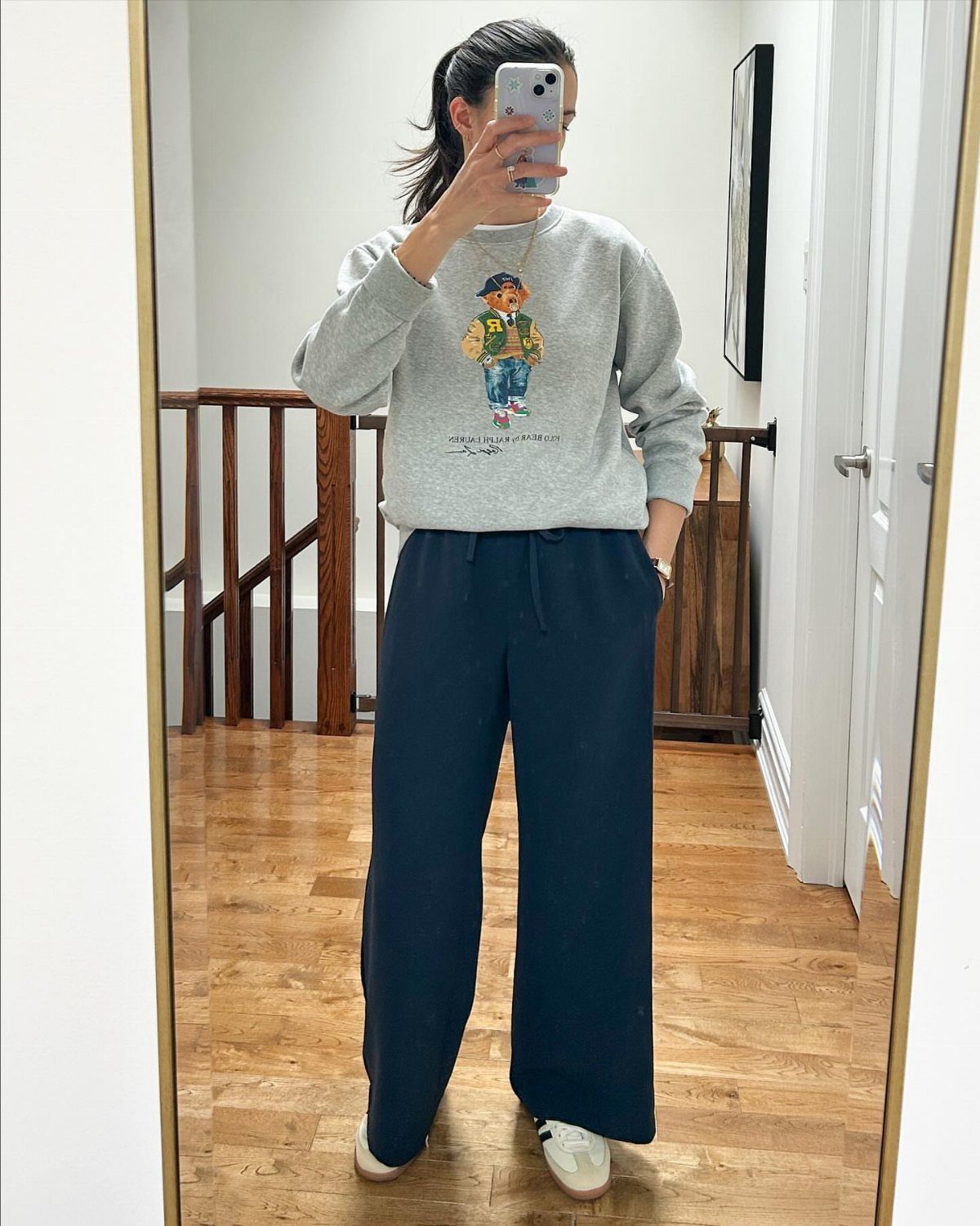 Person wearing a grey Polo Bear sweatshirt and navy blue wide-leg joggers.