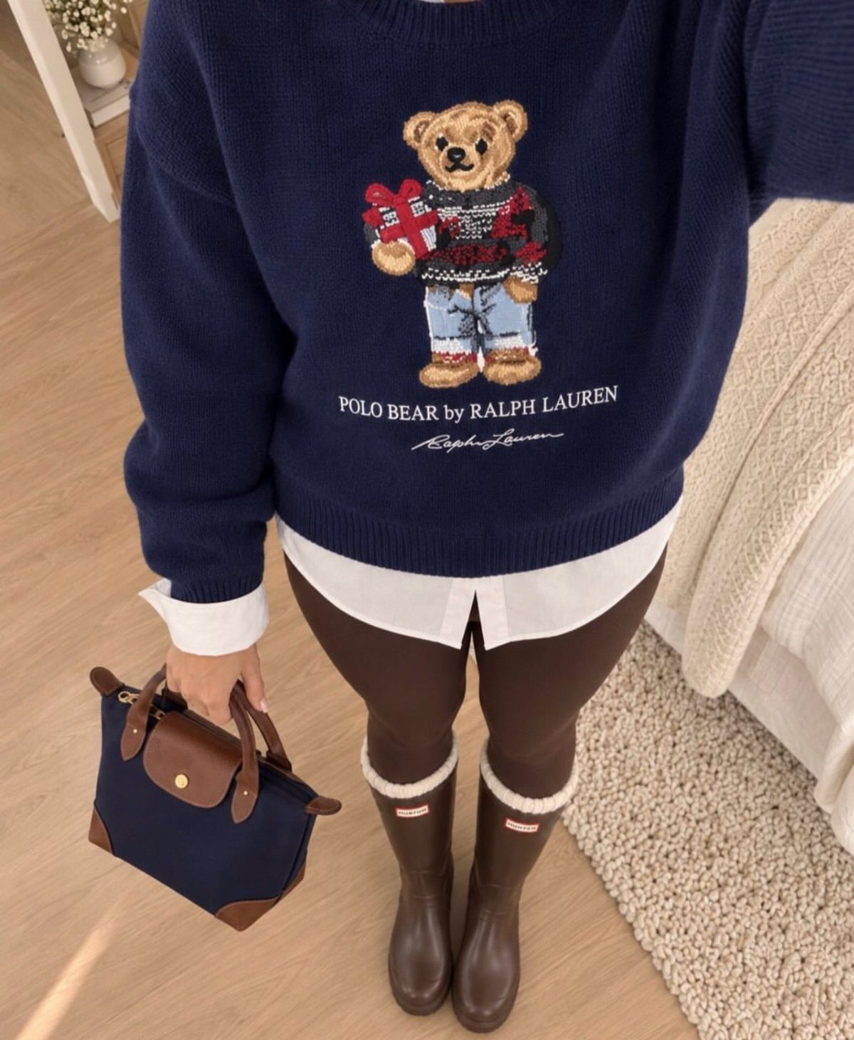 Person wearing a navy Polo Bear sweater, white shirt, brown tights, and brown boots.