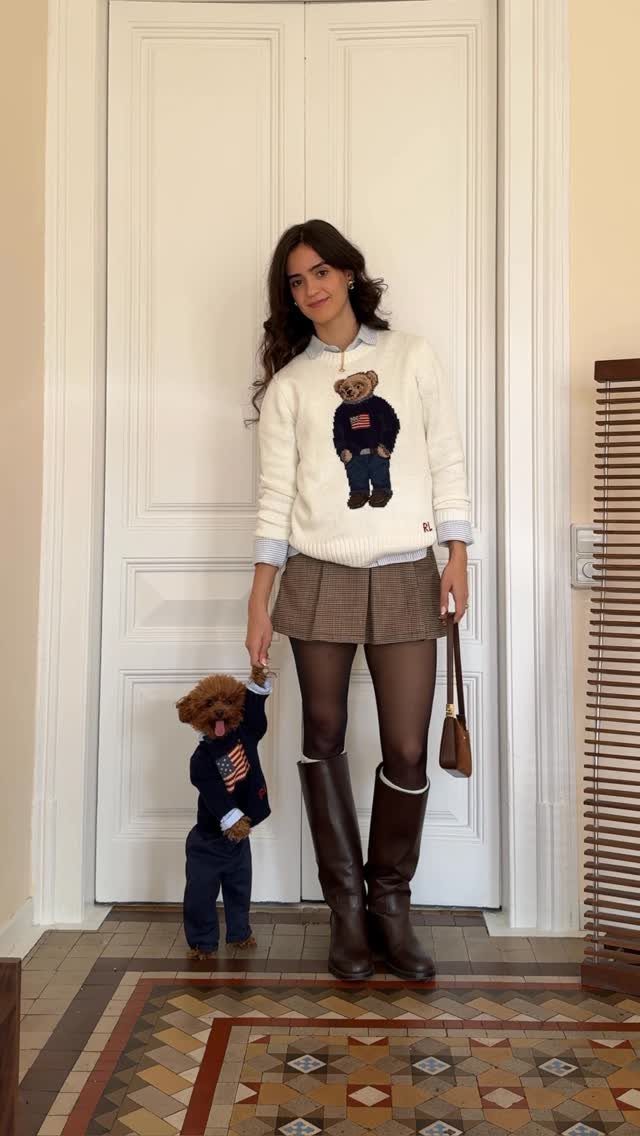 Woman wearing a white Polo Bear sweater, plaid skirt, and brown boots.
