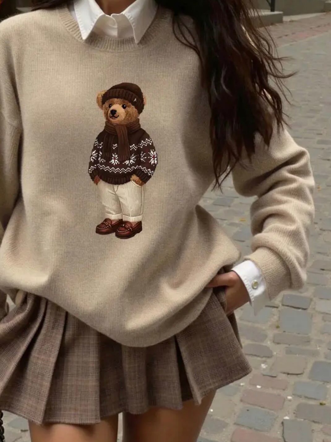 Beige bear sweater with white collared shirt and brown plaid pleated mini skirt.