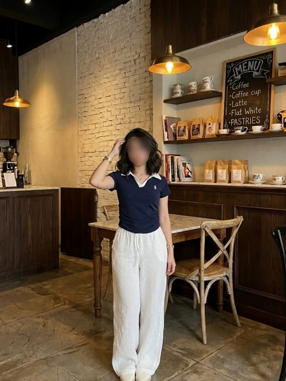 15 Preppy Summer Outfits to Wear All Season Long 2 Woman wearing a navy polo shirt and wide-leg white trousers in a cafe.