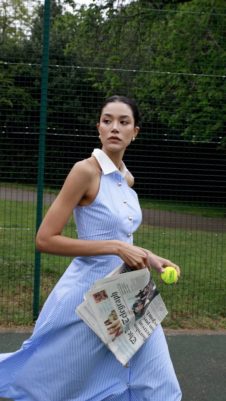 15 Preppy Summer Outfits to Wear All Season Long 8 Woman in a striped sleeveless dress with a white collar on a tennis court.