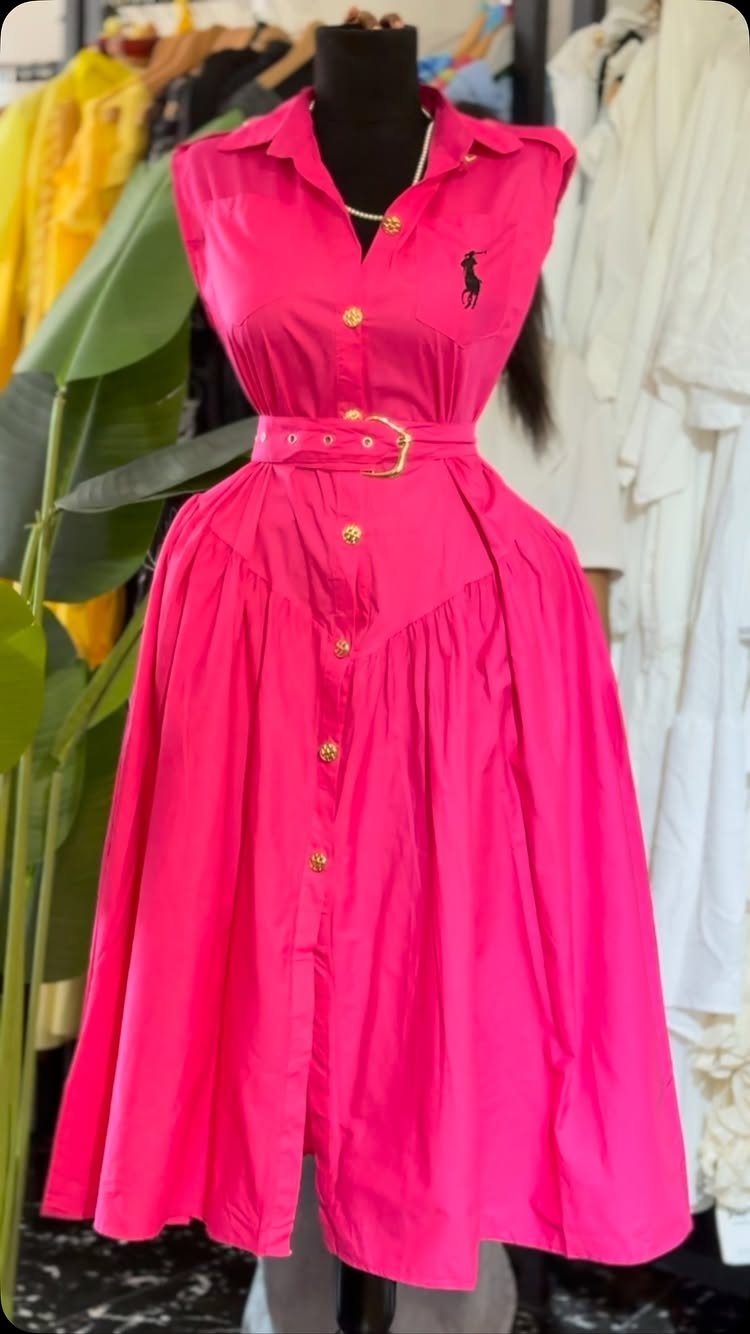 15 Preppy Summer Outfits to Wear All Season Long 13 Bright pink sleeveless button-up dress with gold buttons and matching belt on a mannequin.