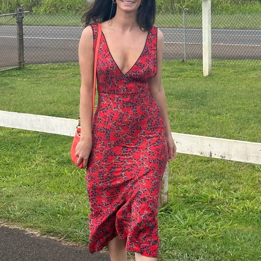 Red Summer Dress: 6 Looks for Warm Days and Nights 3 Woman in a red sleeveless floral midi dress carrying a bright orange shoulder bag outdoors.