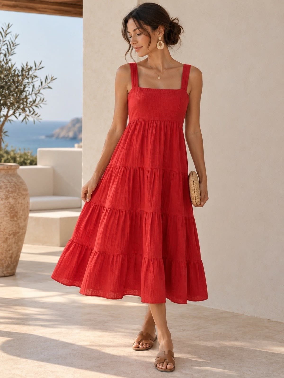 Red Summer Dress: 6 Looks for Warm Days and Nights 5 Woman in a red tiered cotton maxi dress and sandals standing on a sunny patio.