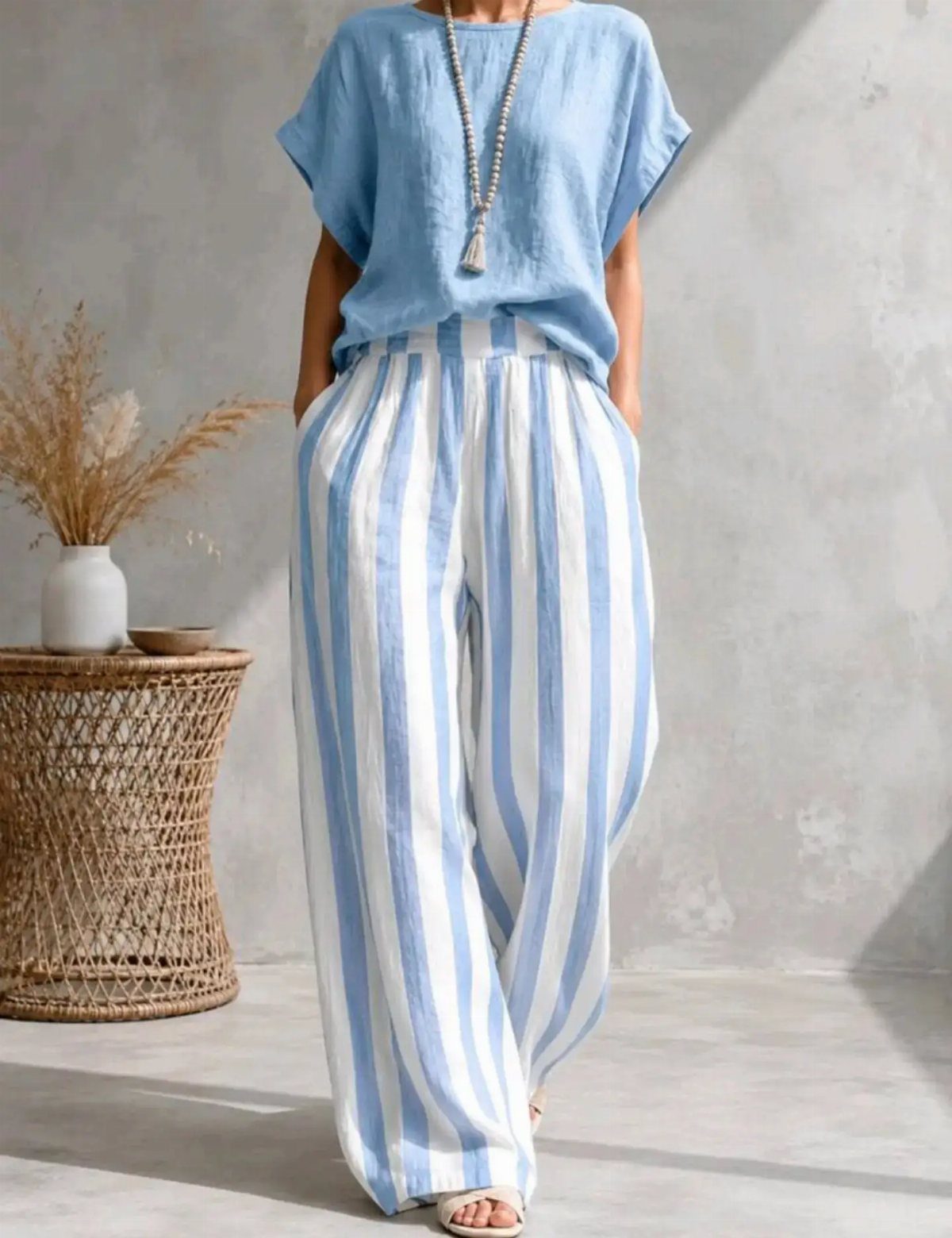 Woman wearing blue and white striped wide-leg linen trousers and a blue top.