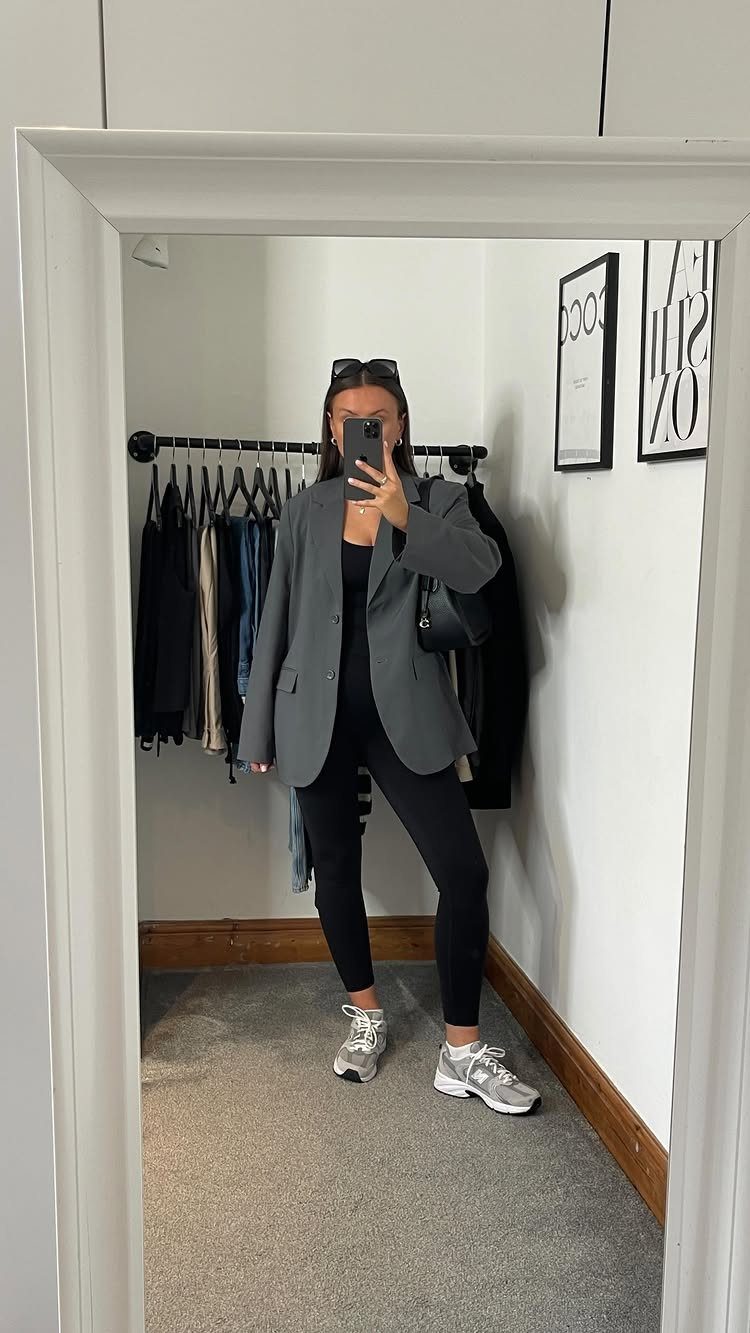12 Sporty Chic Outfits That Work Beyond the Gym 8 Person wearing a grey blazer, black leggings, and silver sneakers in a mirror selfie.