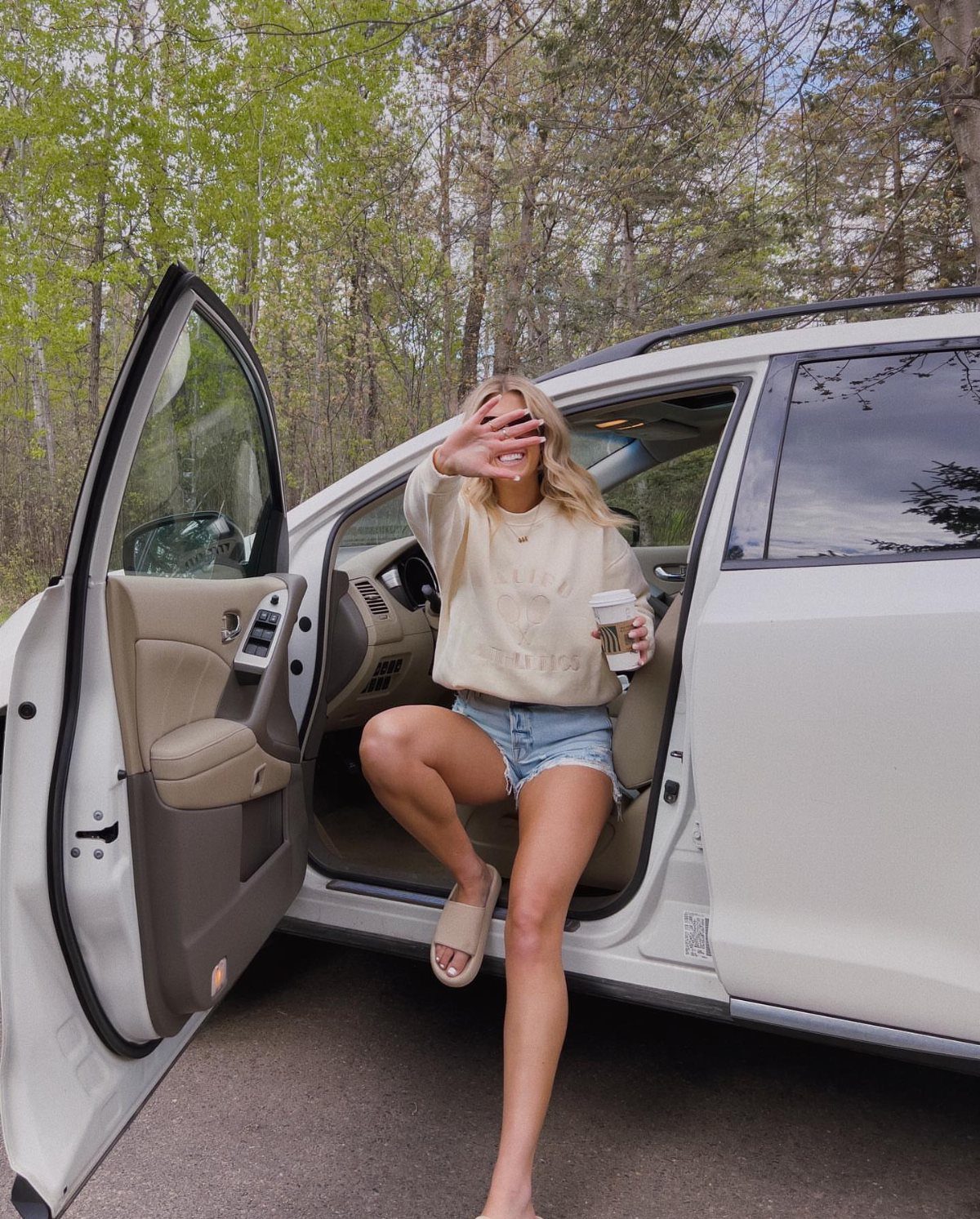 11 Spring Summer Outfits You'll Reach for All Season Long 9 Woman in cream shirt and denim shorts stepping out of a white SUV.