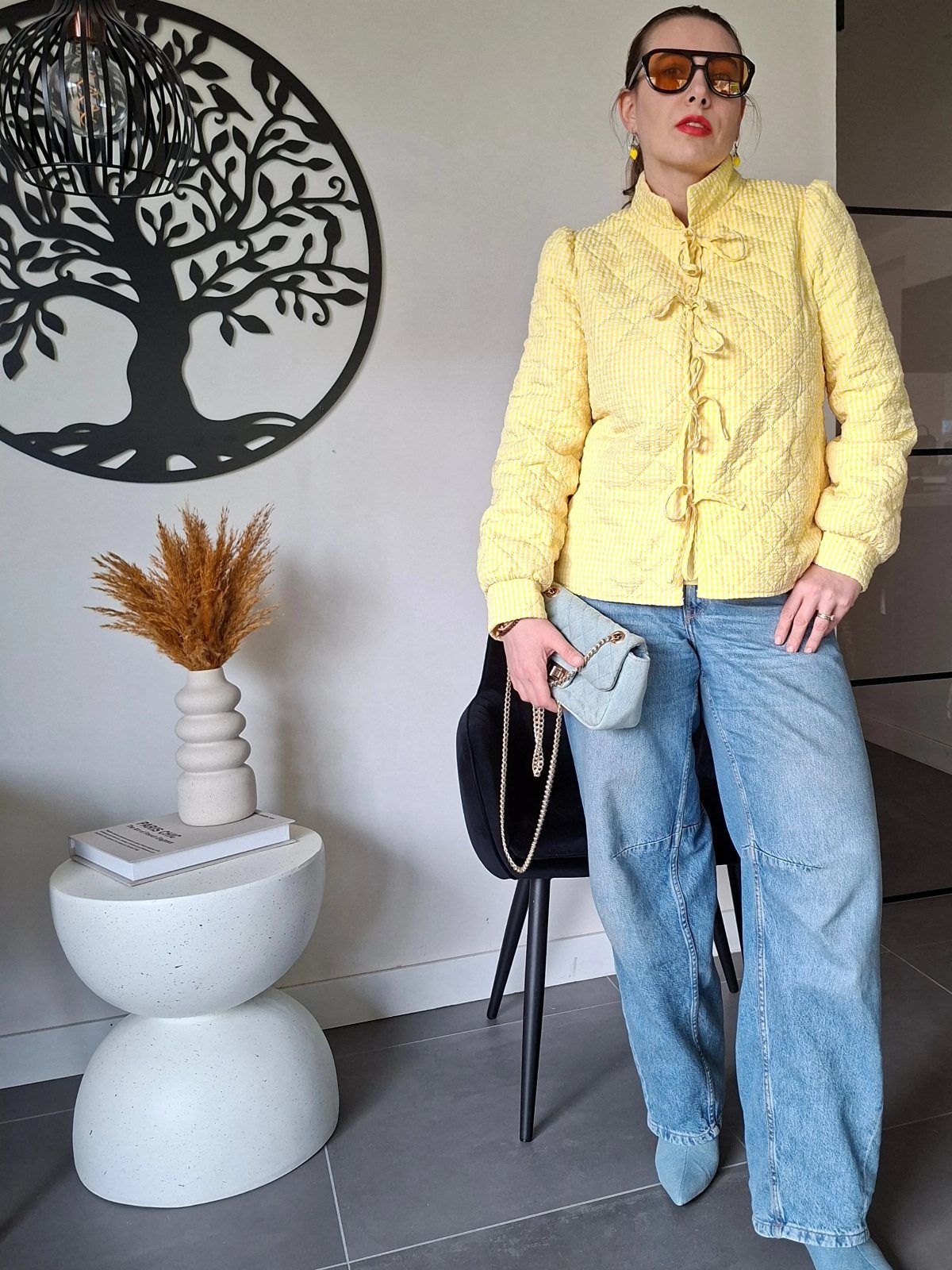 11 Spring Summer Outfits You'll Reach for All Season Long 1 Woman in yellow jacket and light blue wide-leg jeans posing indoors.