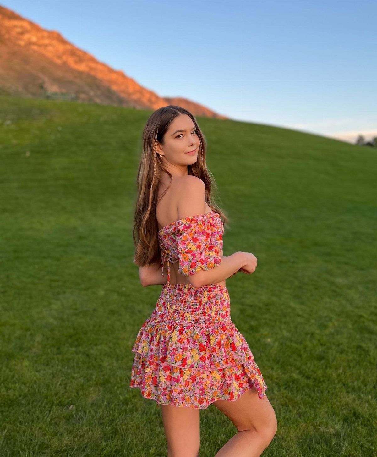 11 Spring Summer Outfits You'll Reach for All Season Long 6 Woman wearing a colorful floral off-the-shoulder crop top and matching ruffled mini skirt.