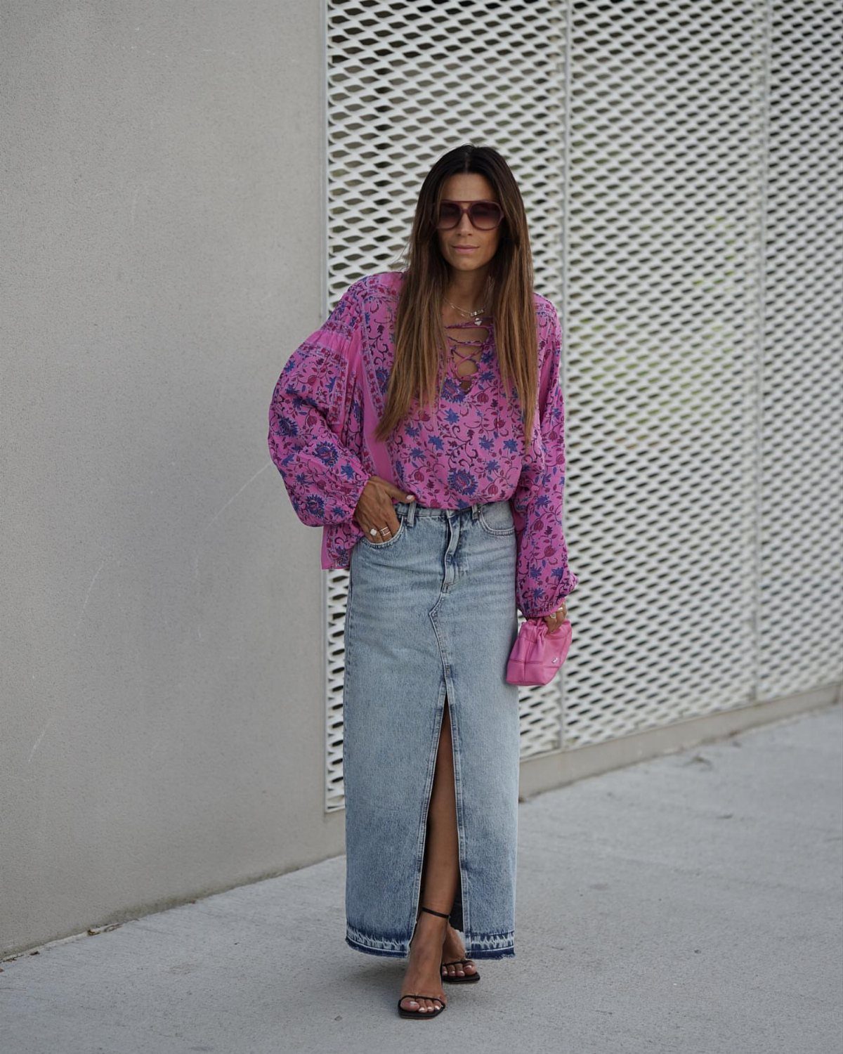 Woman in purple floral blouse and long denim skirt with a front slit.