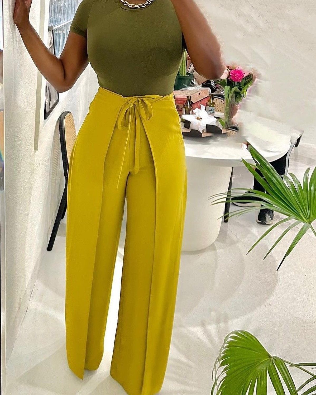 Person wearing a fitted olive green top and high-waisted mustard yellow wide-leg trousers.