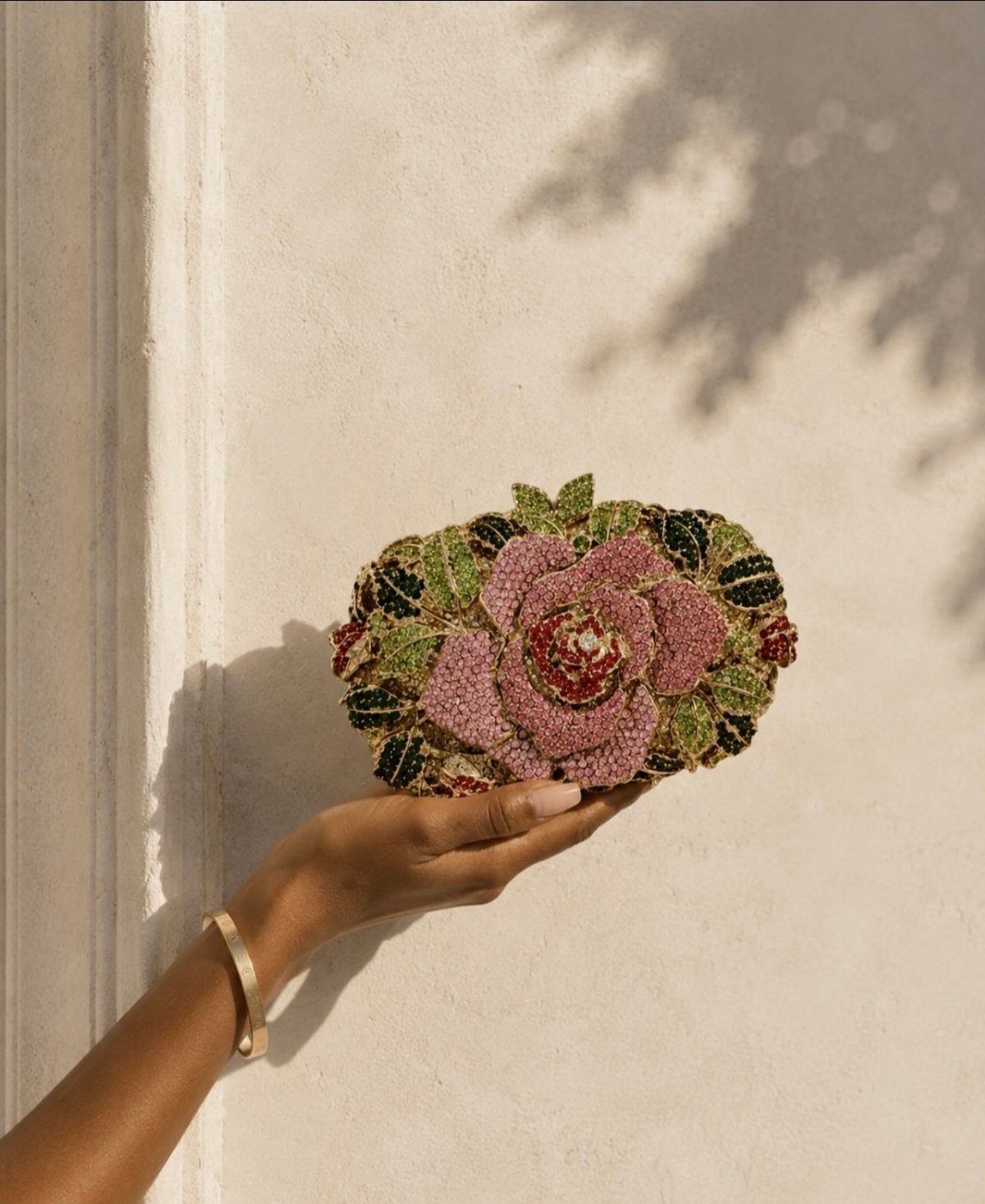 12 Tea Party Outfit Ideas for Women: Dresses, Hats & Accessories 11 A hand holding an oval beaded clutch bag with a large pink rose design.