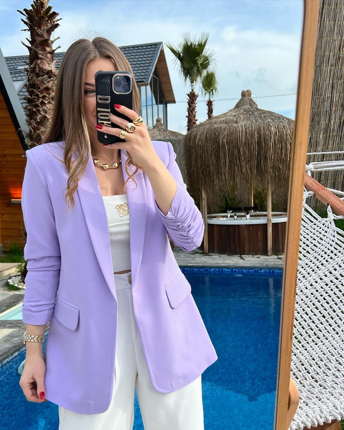 12 Tea Party Outfit Ideas for Women: Dresses, Hats & Accessories 7 Woman in a lavender pastel blazer and white trousers posing for a mirror selfie by a pool.